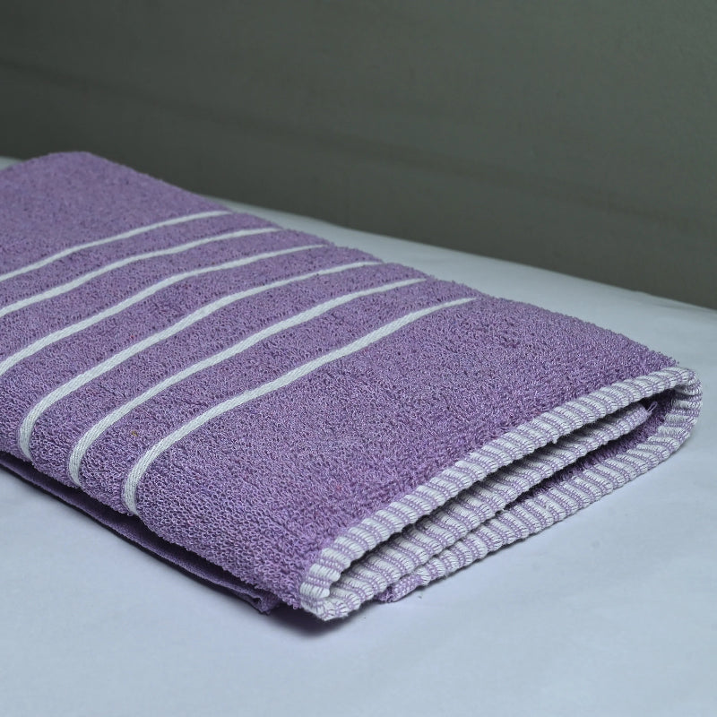Folded purple towel with white stripes on a light surface