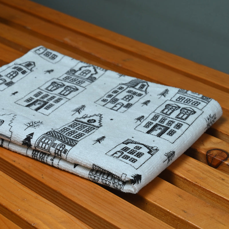 a white black printed towel placed on a wooden table with grey background.