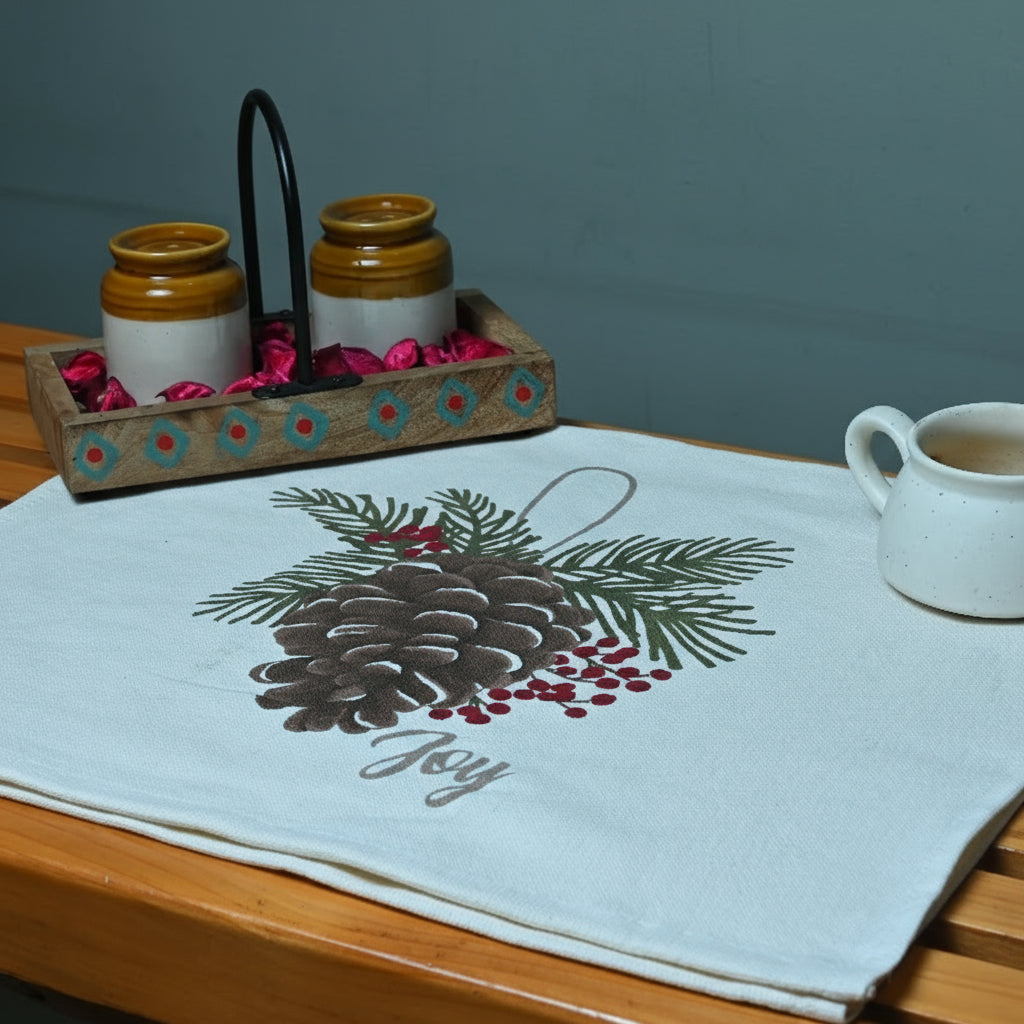 Table setting with a placemat featuring a pine cone design, two mugs, and a decorative tray.