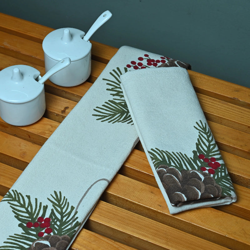 Two printer tea towels with winter designs on a wooden surface.