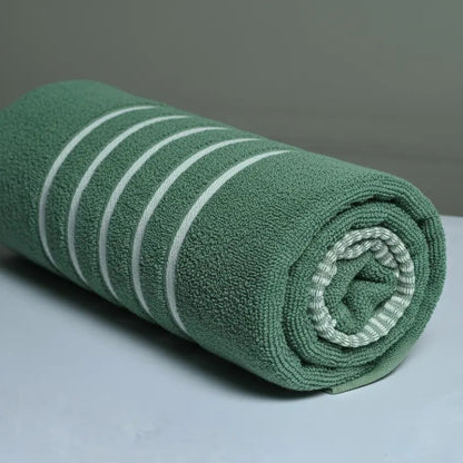 Rolled green towel with white stripes on a gray background
